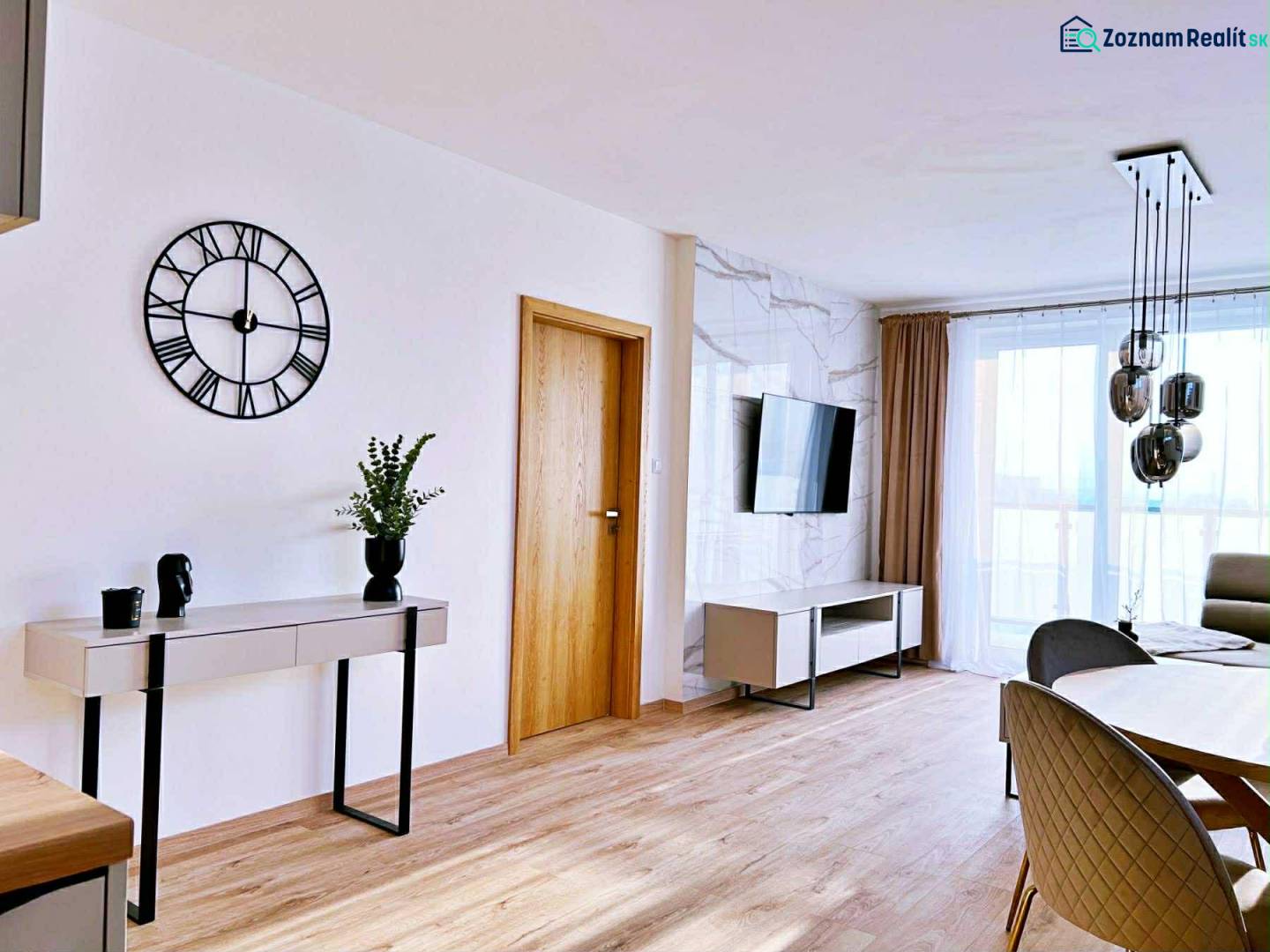 Wohnzimmer in einer 3-Zimmer-Wohnung mit Holzboden, Tisch und Fernseher.