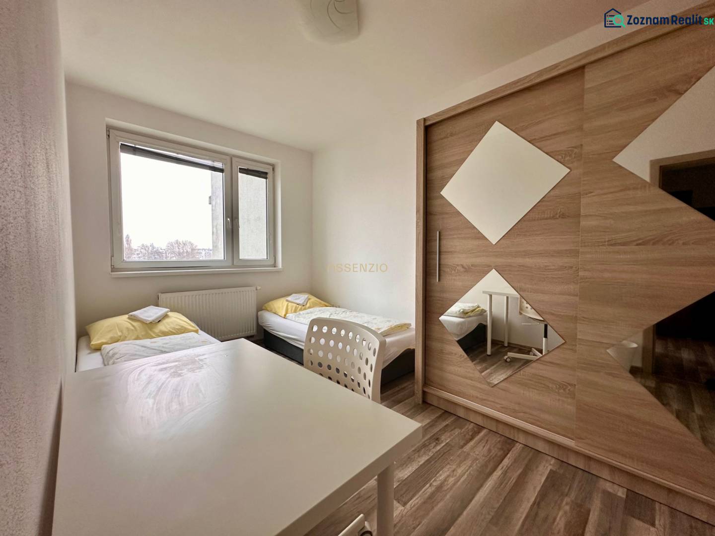 Schlafzimmer mit zwei Betten, einem weißen Tisch und einem Schrank in einer 3-Zimmer-Wohnung.