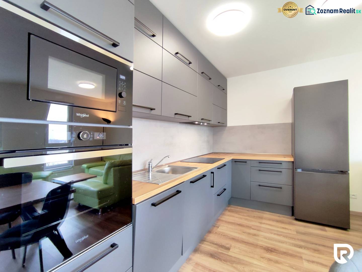 Küche in einer 3-Zimmer-Wohnung mit Holzboden, graue Schränke, Einbaugeräte.