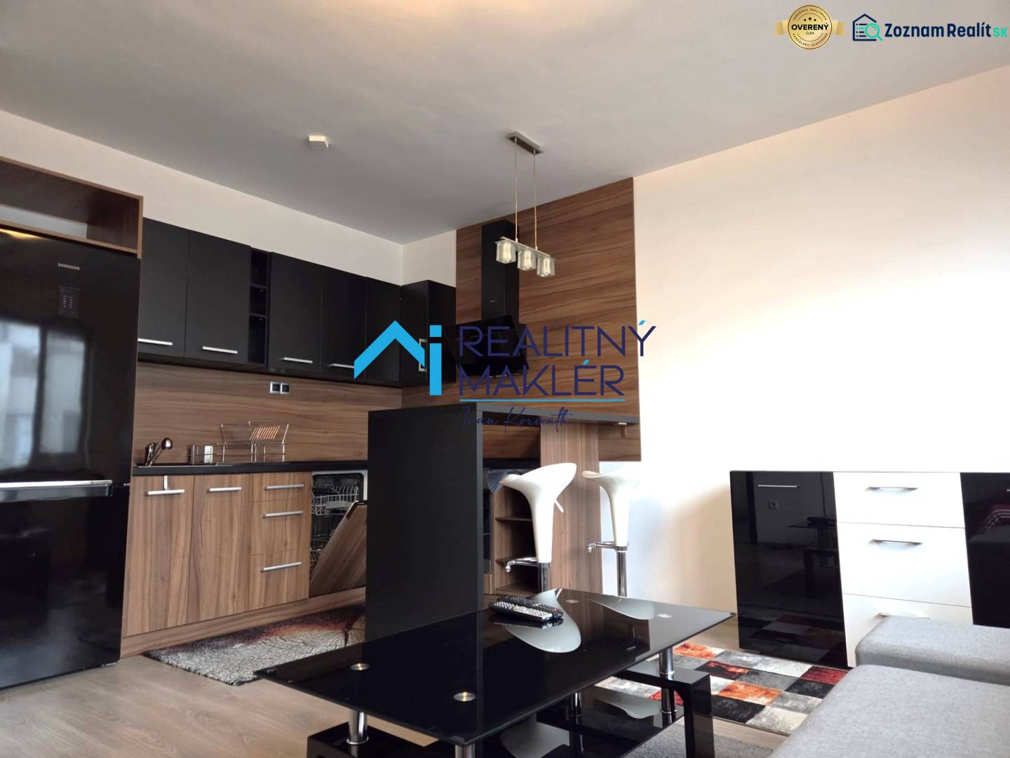 Küche in einer Einzimmerwohnung mit schwarzen Schränken, Boden mit Holzdekor.