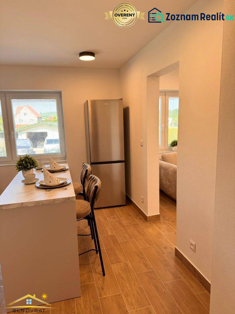 Küche in einer 2-Zimmer-Wohnung mit Bar, Holzboden und Kühlschrank.