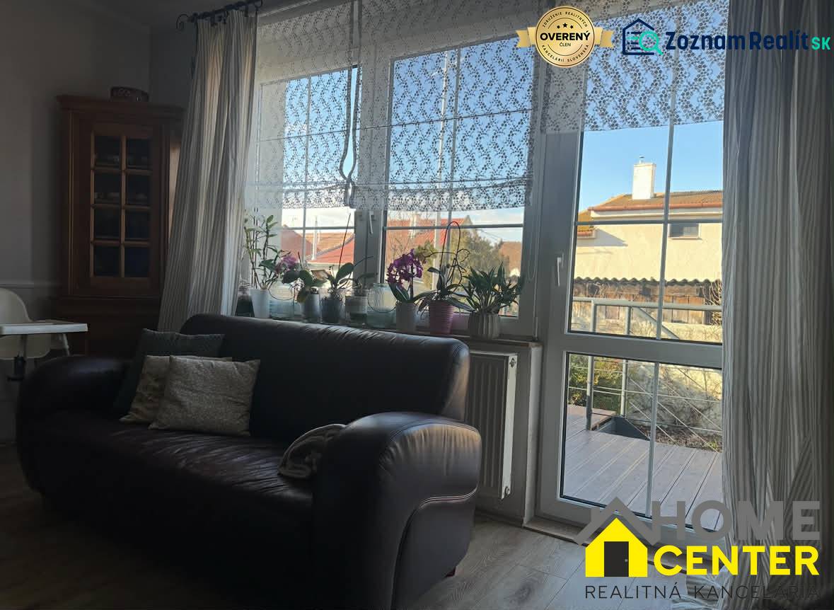 Ledersofa und Fenster mit Spitzenvorhängen in einem Einfamilienhaus mit Holzboden.