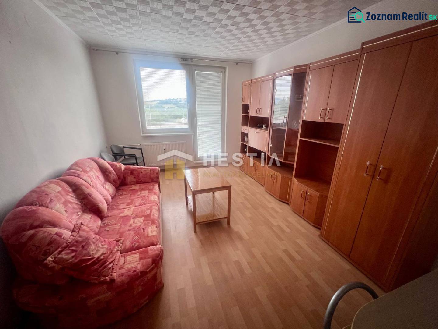 Ein Zimmer in einer 3-Zimmer-Wohnung mit einem Sofa, Schränken und einem Tisch auf einem hellen Boden.