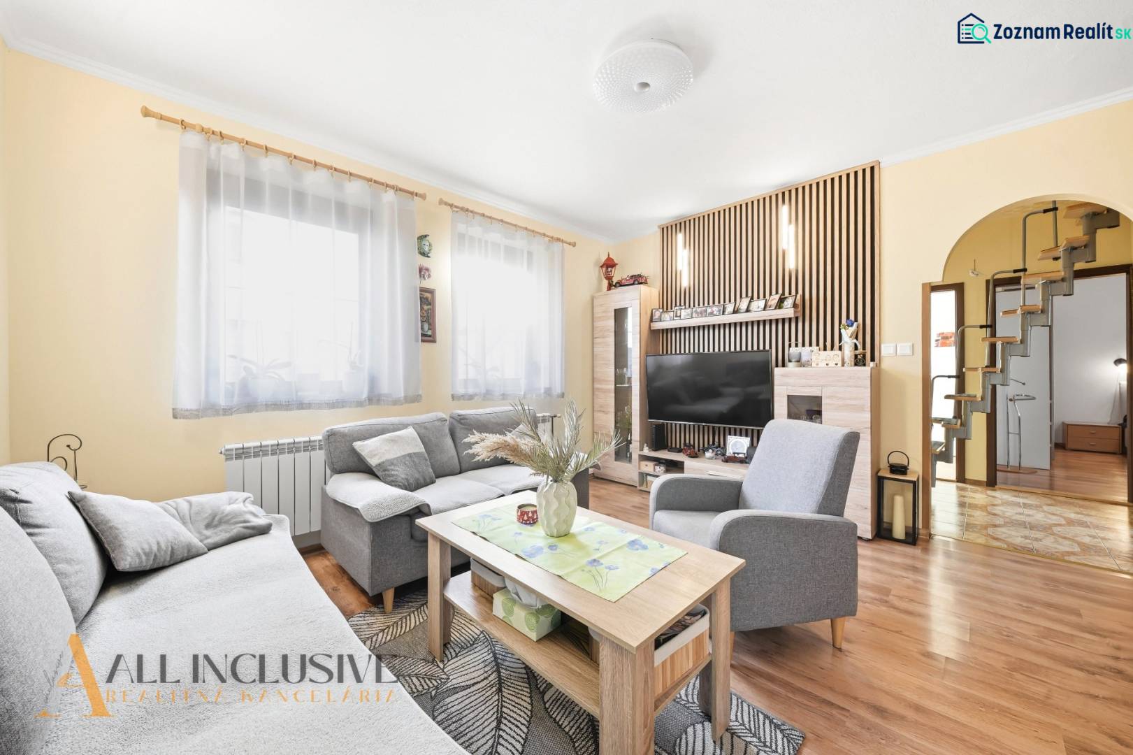 Wohnzimmer in einem Einfamilienhaus mit Sofa, Tisch, Fernseher und Holzboden.