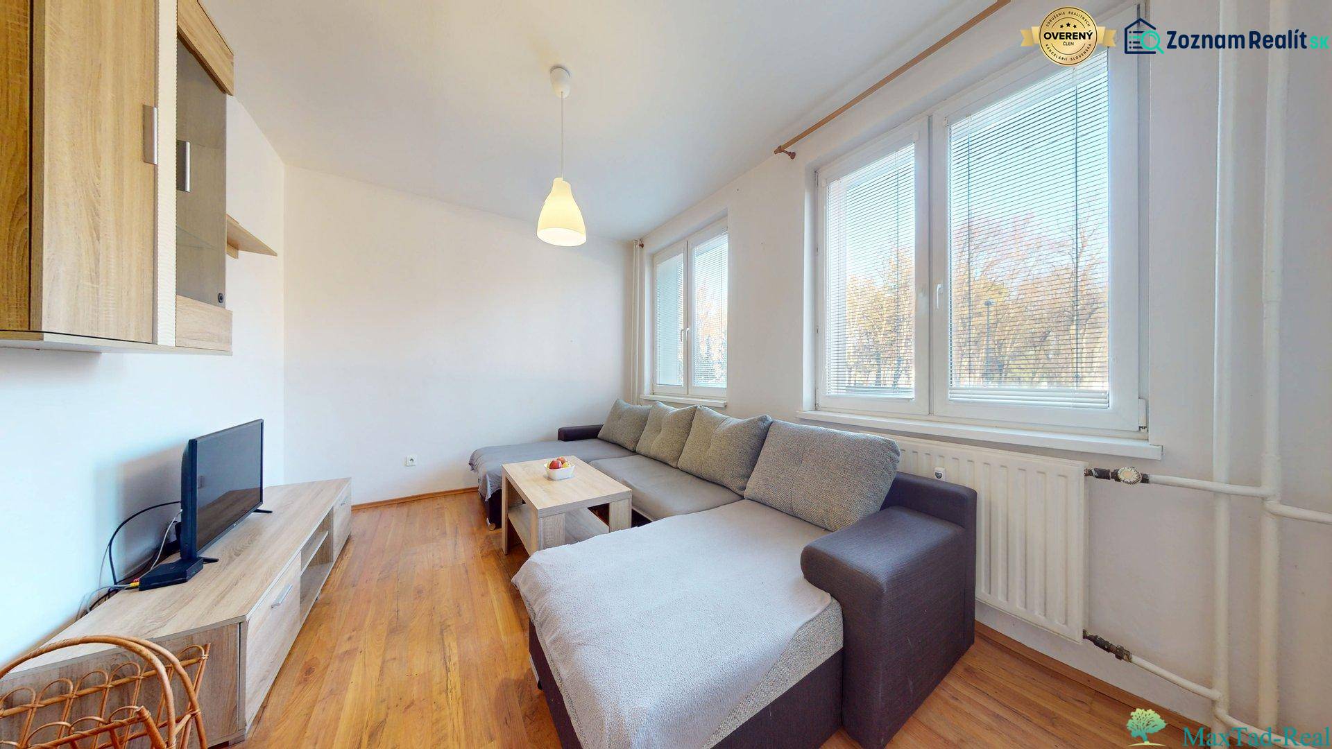 Wohnzimmer in einer 3-Zimmer-Wohnung mit Sofa, Fernseher und Holzboden.