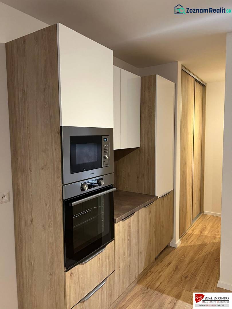 Küchenbereich einer Zweizimmerwohnung mit Holzboden und Einbauschränken.