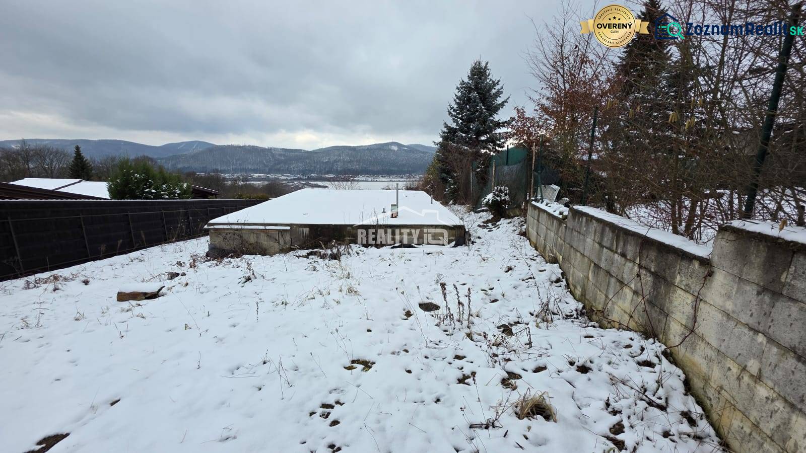 Verschneite Erholungsgrundstücke in Považská Bystrica mit Blick auf die Berge und gepflanzten Bäumen.