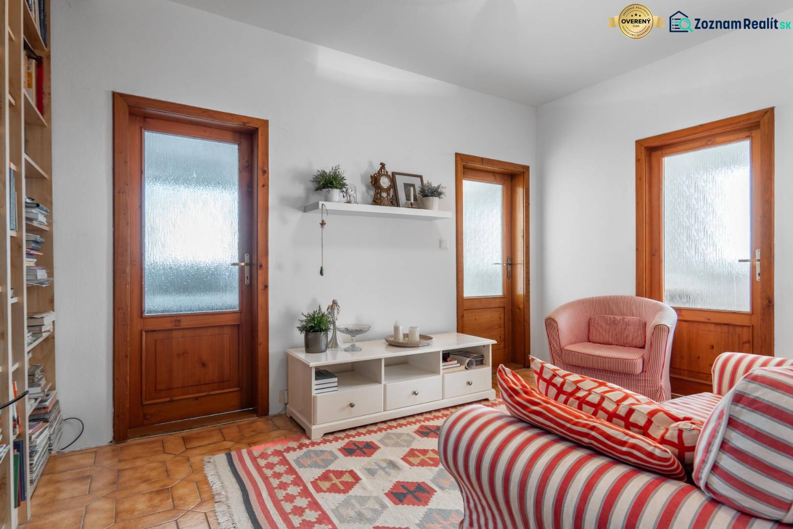 Wohnzimmer in einer 4-Zimmer-Wohnung mit rot gestreiften Sesseln und einem Regal an der Wand.