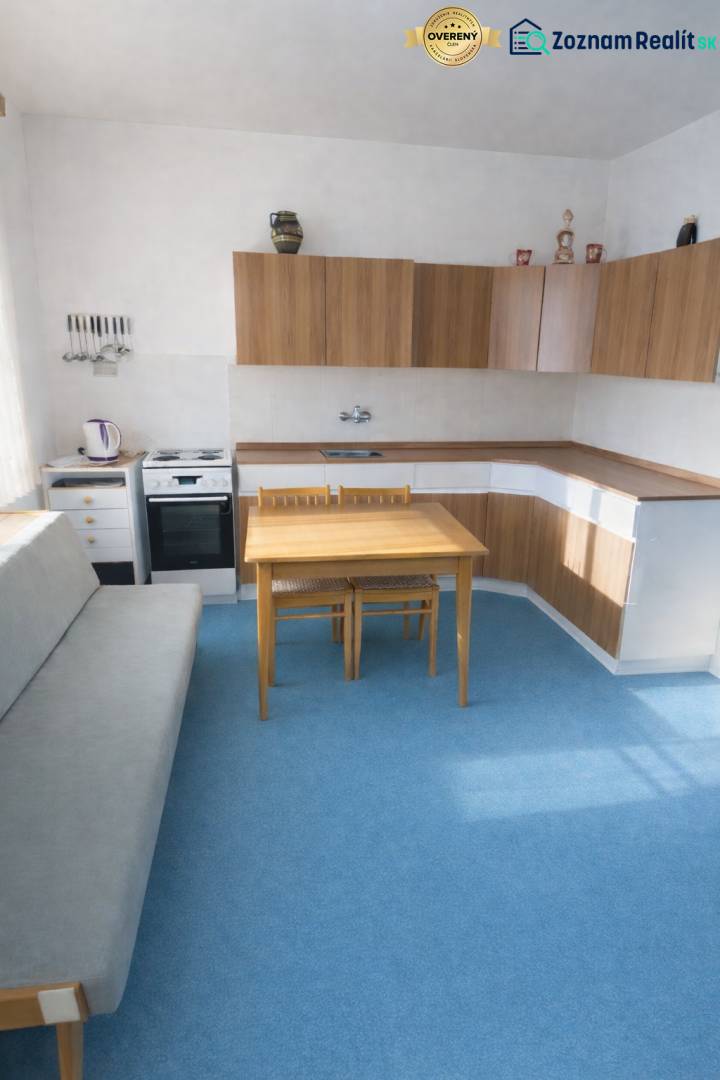 Eine Küche in einem Einfamilienhaus mit blauem Teppich und Holzschränken.