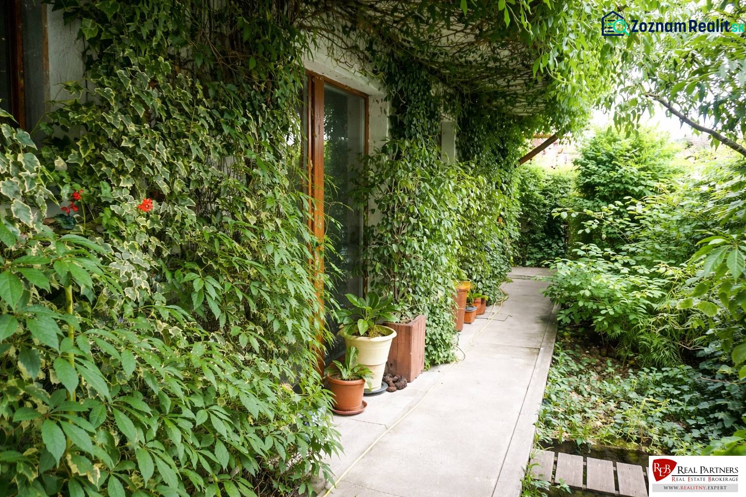 Der Garten einer 3-Zimmer-Wohnung in der Šancová-Straße in Pezinok mit üppigem Grün und einem Gehweg.