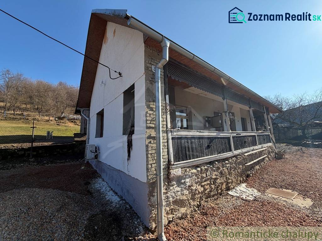 Das Äußere eines Einfamilienhauses in Ratkovské Bystré mit sonnigem Wetter und einem steinernen Fundament.