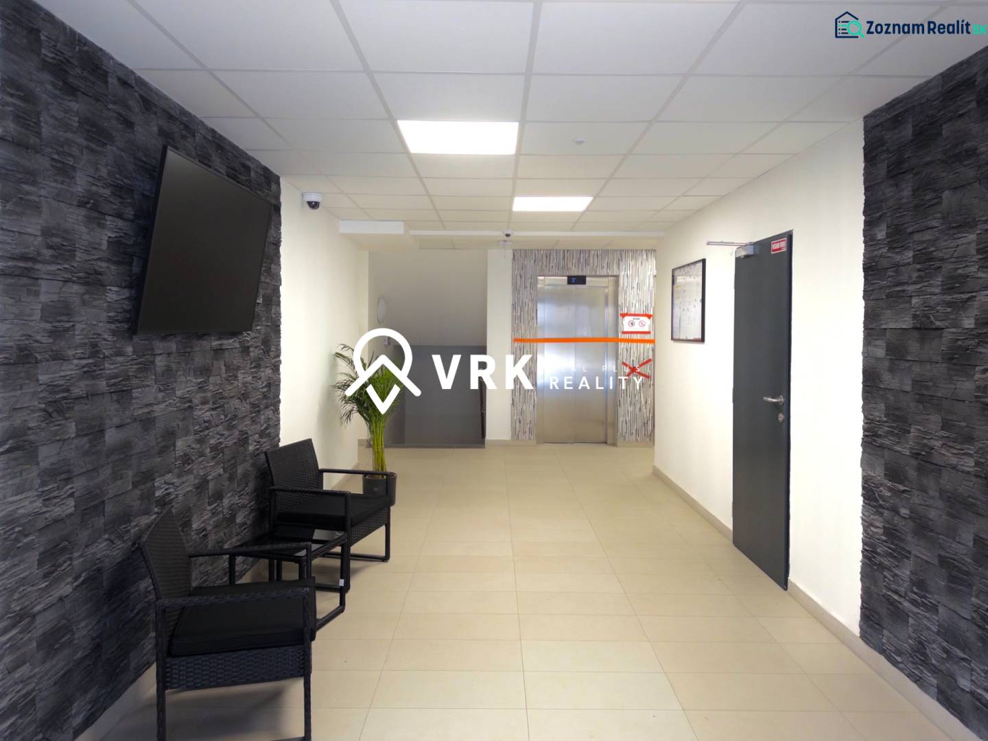 Flur in einer 3-Zimmer-Wohnung mit Fernseher an der Wand und Aufzug im Hintergrund.