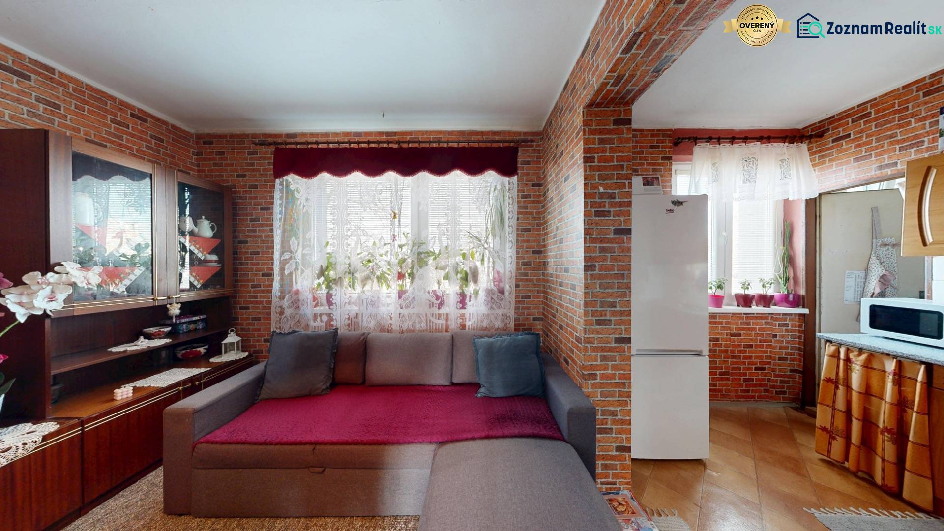 Wohnzimmer in einer 4-Zimmer-Wohnung mit Sofa, Backsteinwänden und Küchenzeile.