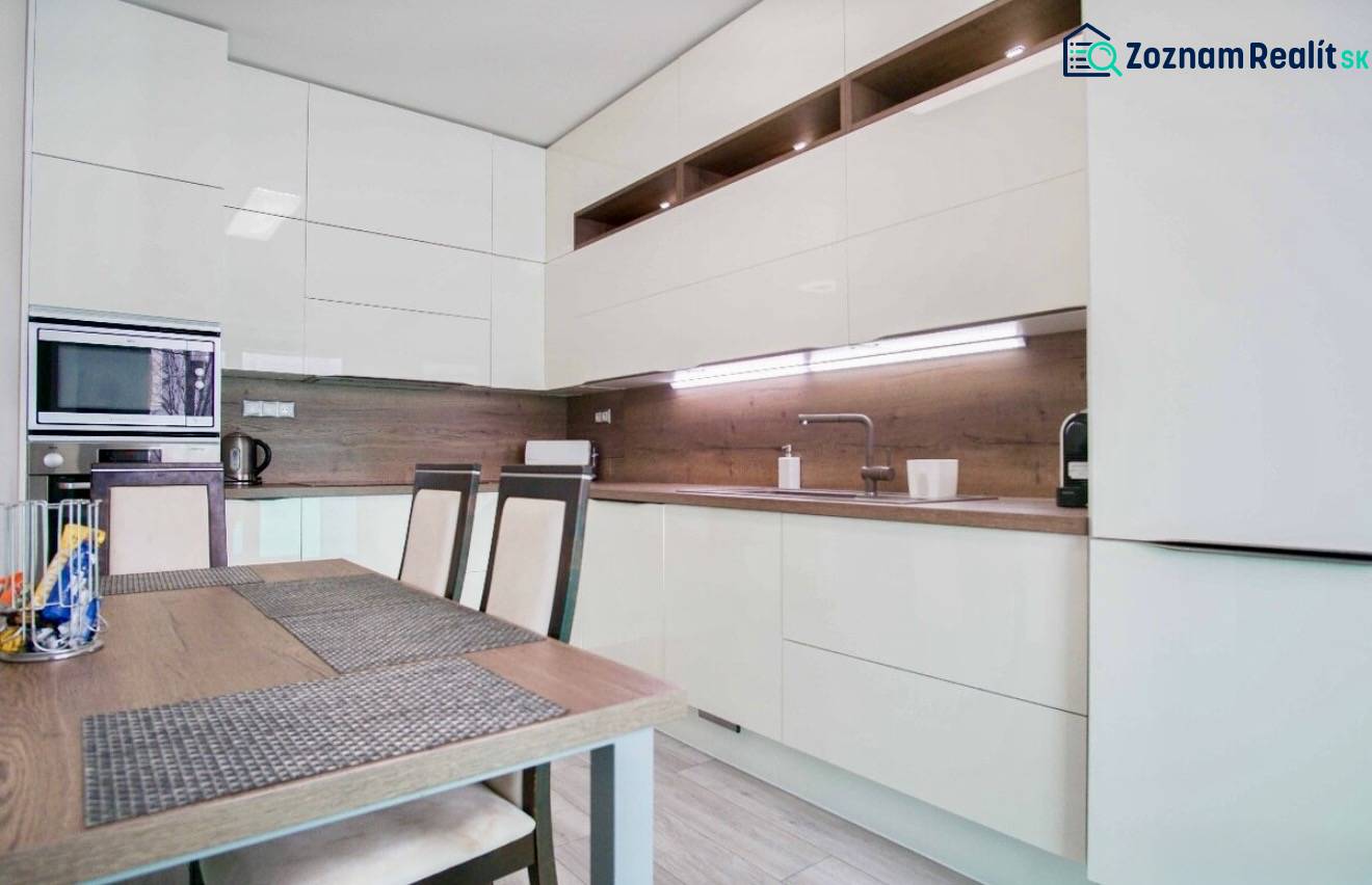 Küche in einer 3-Zimmer-Wohnung mit glänzenden Schränken und Holzwanddekoration.