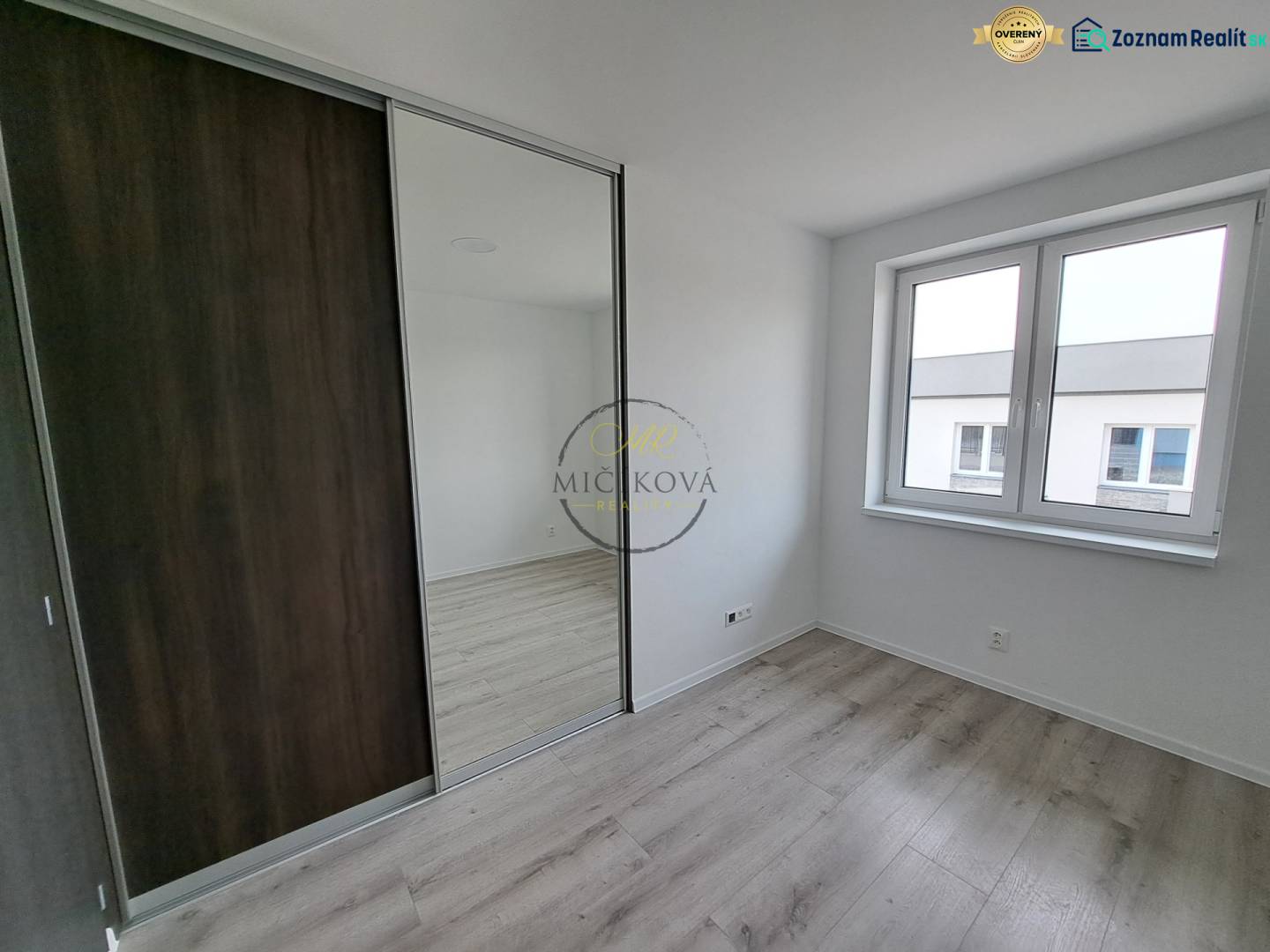 Ein Zimmer in einem Einfamilienhaus mit einem Boden in Holzoptik und einem großen Spiegelschrank.