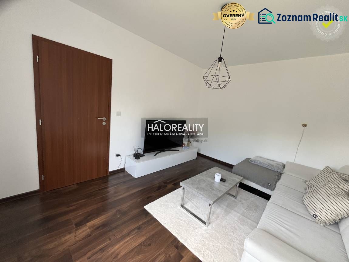Wohnzimmer in einem Einfamilienhaus mit dunklem Boden, weißem Sofa und TV-Tisch.