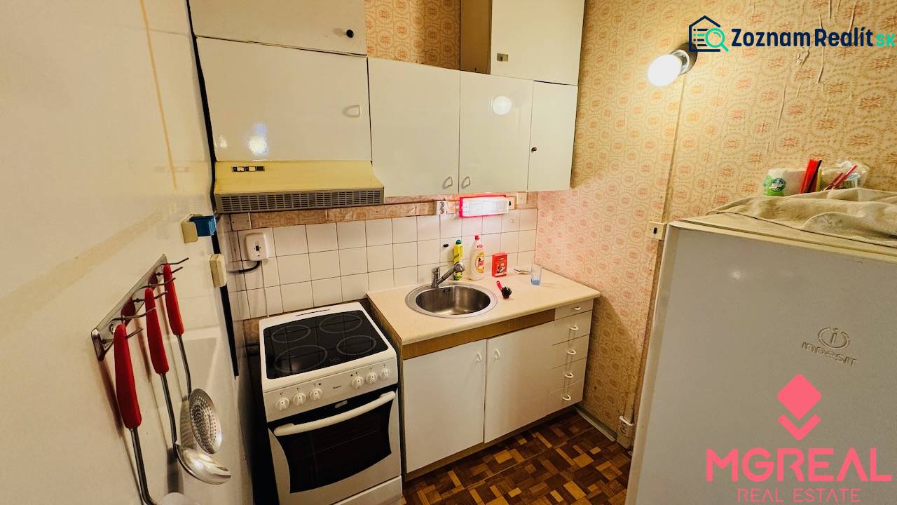Küche in einer 2-Zimmer-Wohnung, weiße Schränke, Herd, Spüle, Boden mit Holzdekor.