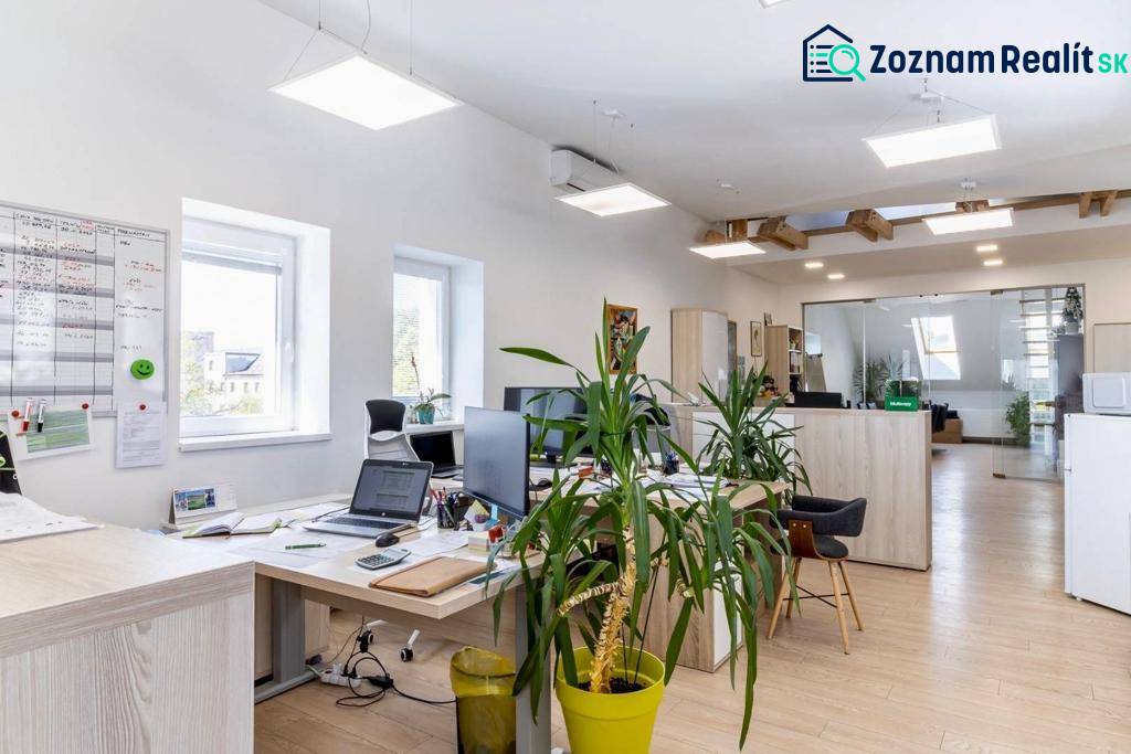 Beleuchtete Büros mit Computern, Pflanzen und einem Boden in Holzoptik.