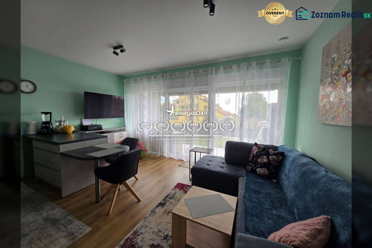 Wohnzimmer in einem Ferienapartment mit Holzboden, Sofa und Fernseher.