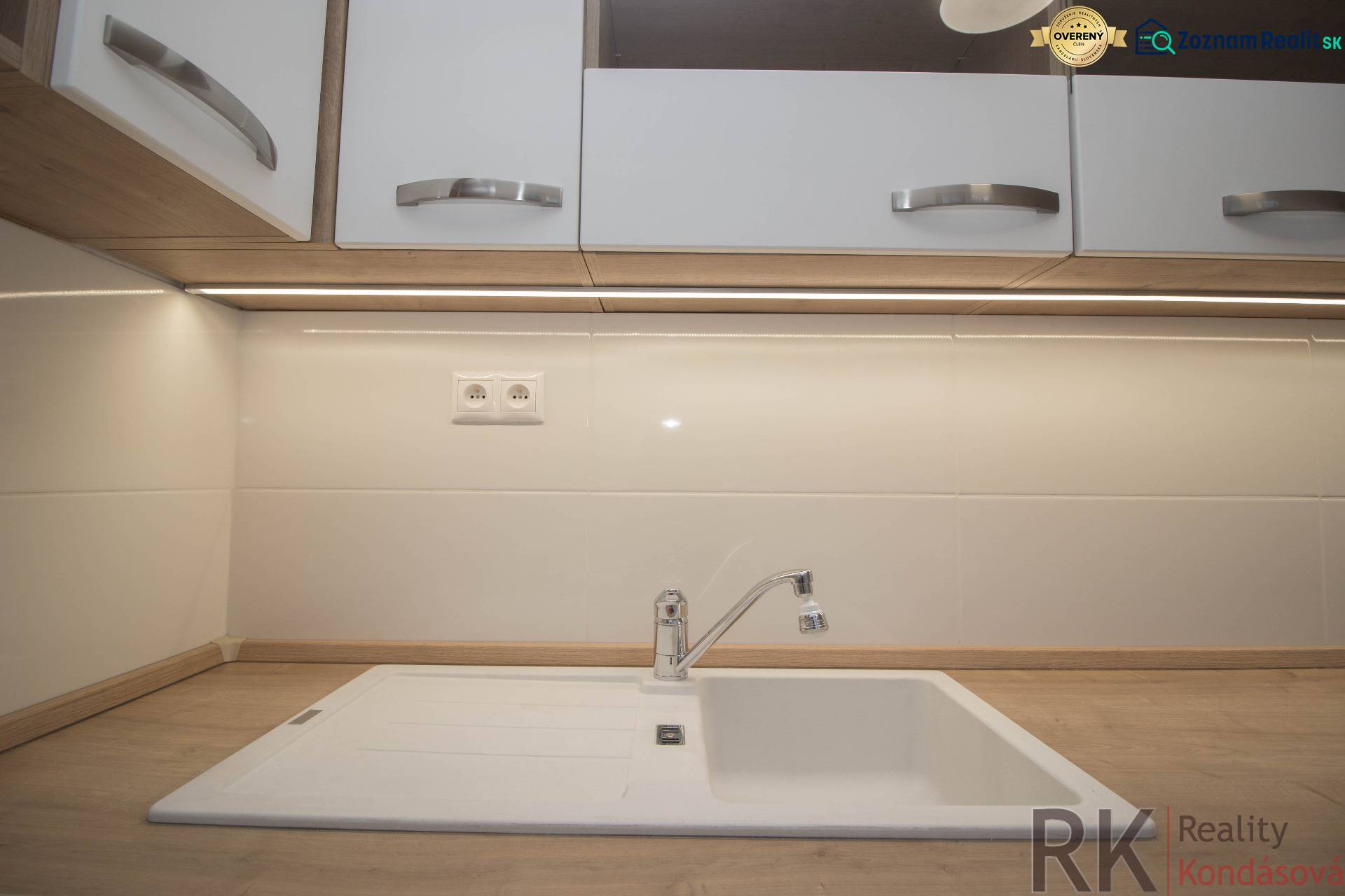 Küchenarbeitsplatte mit Holzdekor und weißem Spülbecken in einer 2-Zimmer-Wohnung.