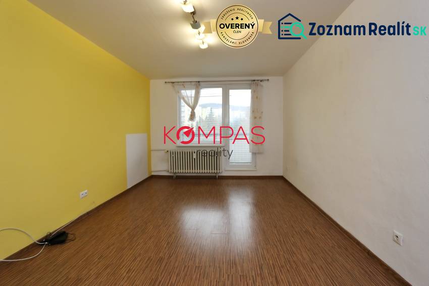 Ein Zimmer in einer 3-Zimmer-Wohnung mit einem Boden in Holzoptik und einer gelben Wand.