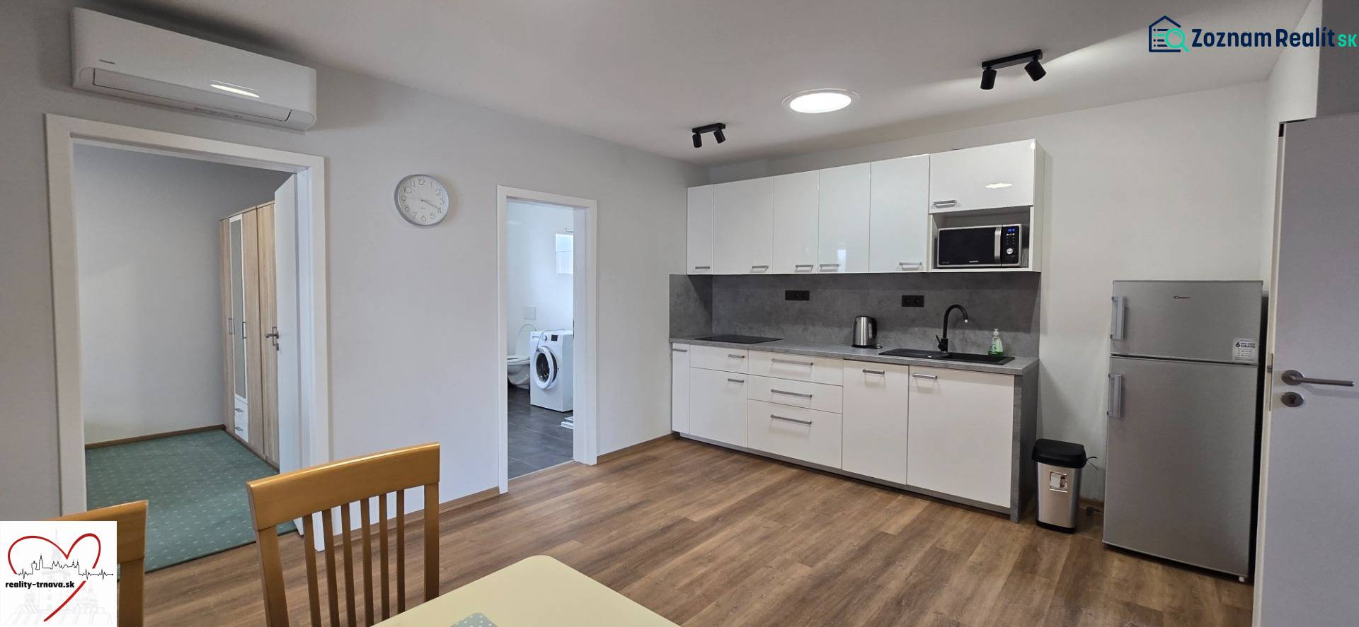 Küche mit weißen Schränken und Geräten in einer 3-Zimmer-Wohnung, Boden mit Holzdekor.