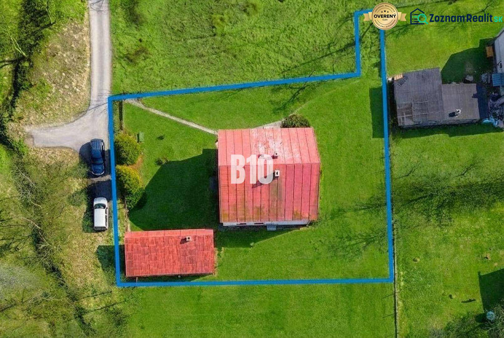 Ein Einfamilienhaus in Raková mit eingezäuntem Grundstück und angrenzenden Gebäuden, umgeben von Grünflächen.