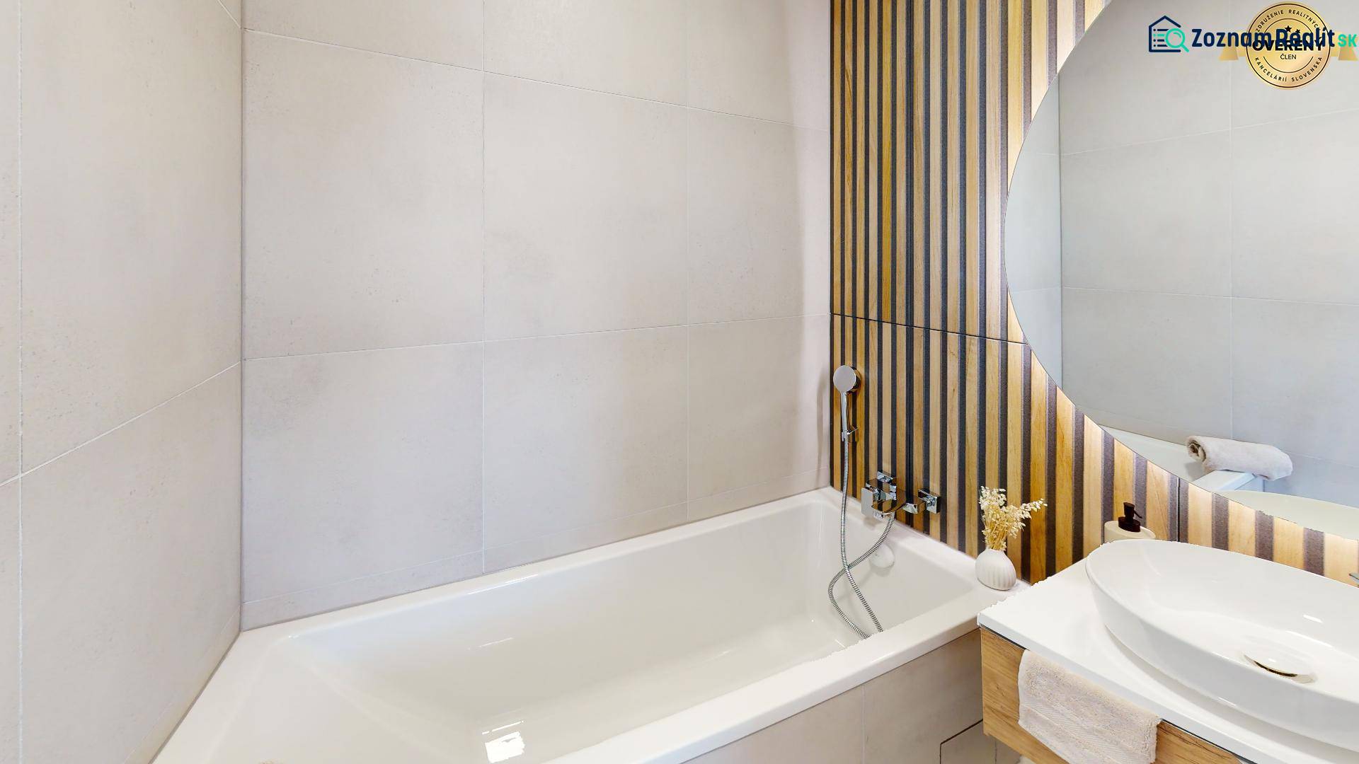 Badezimmer mit Badewanne, Waschbecken und dekorativer Holzverkleidung an der Wand.
