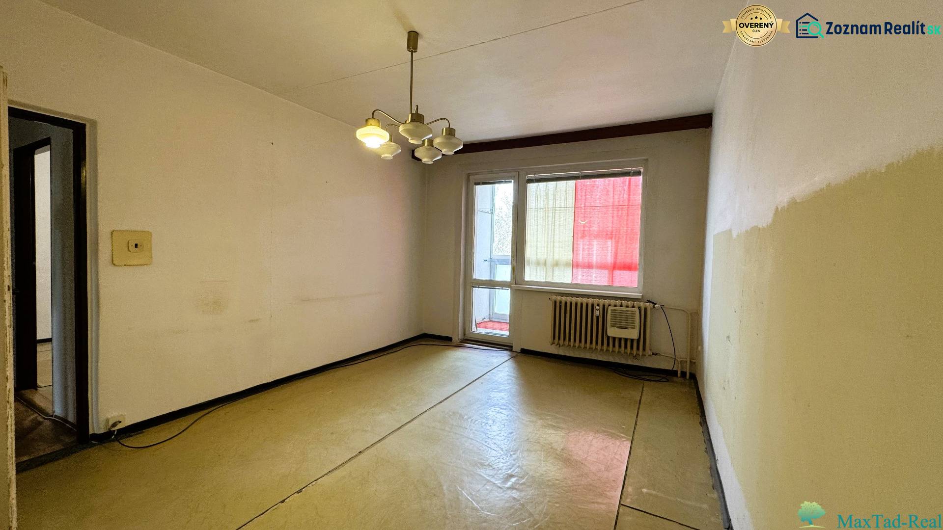 Ein Zimmer in einer 3-Zimmer-Wohnung mit Balkon, einfache Wände und Beleuchtung.