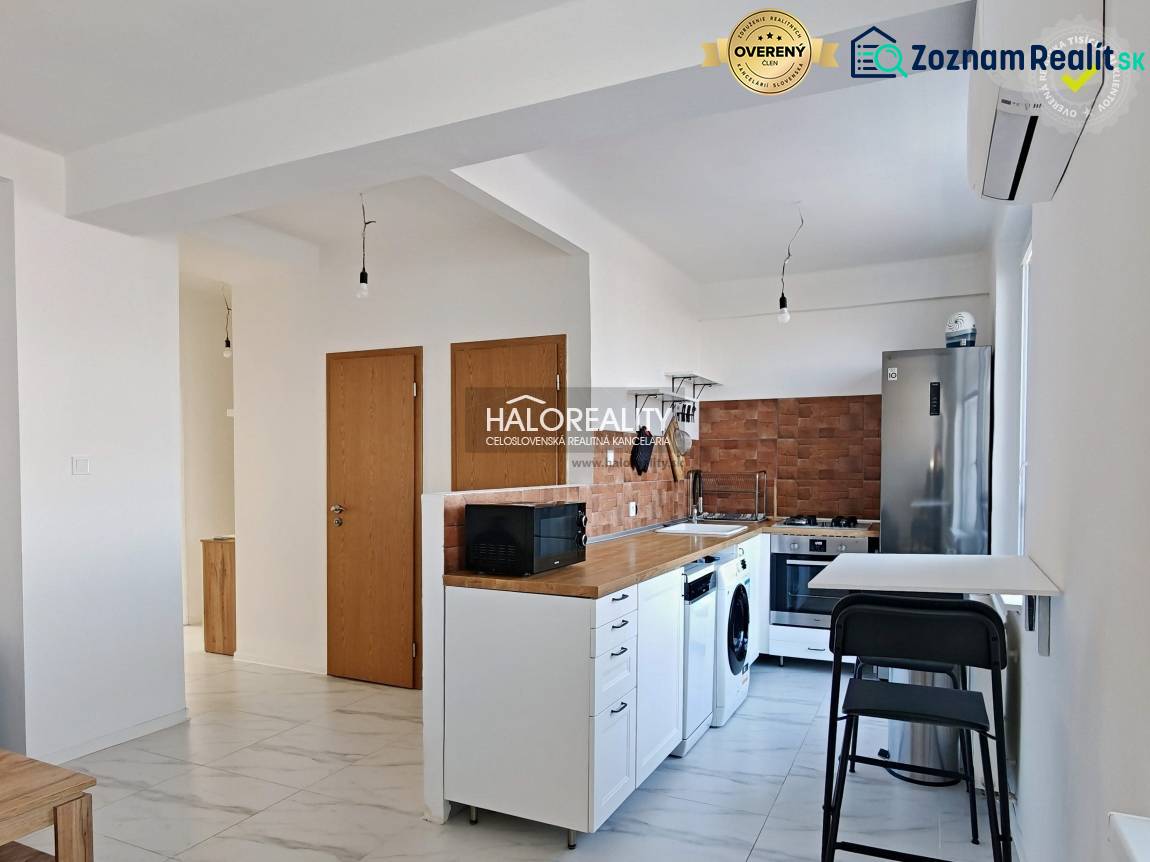 Küche in einer 3-Zimmer-Wohnung mit weißer Küchenzeile, Geräten und Holzelementen.