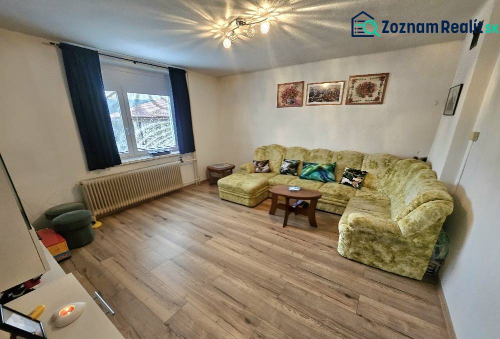 Wohnzimmer in einem Einfamilienhaus mit Sofa, Sesseln und einem Holzboden.