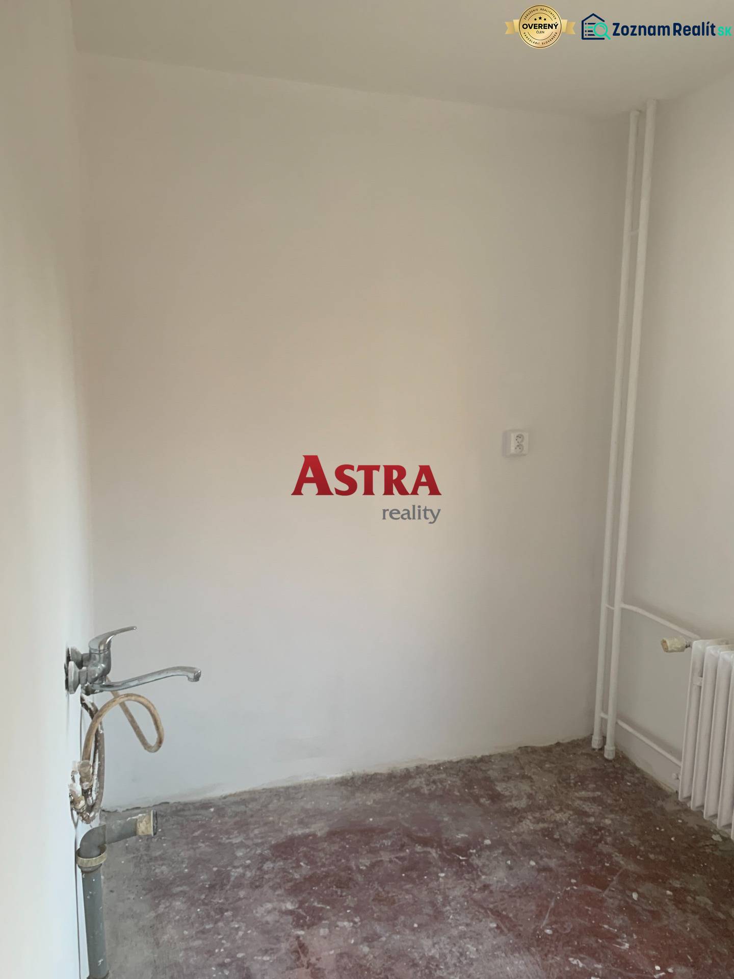 Ein leerer Raum in einer 2-Zimmer-Wohnung ohne Bodenbelag und mit Waschbecken.