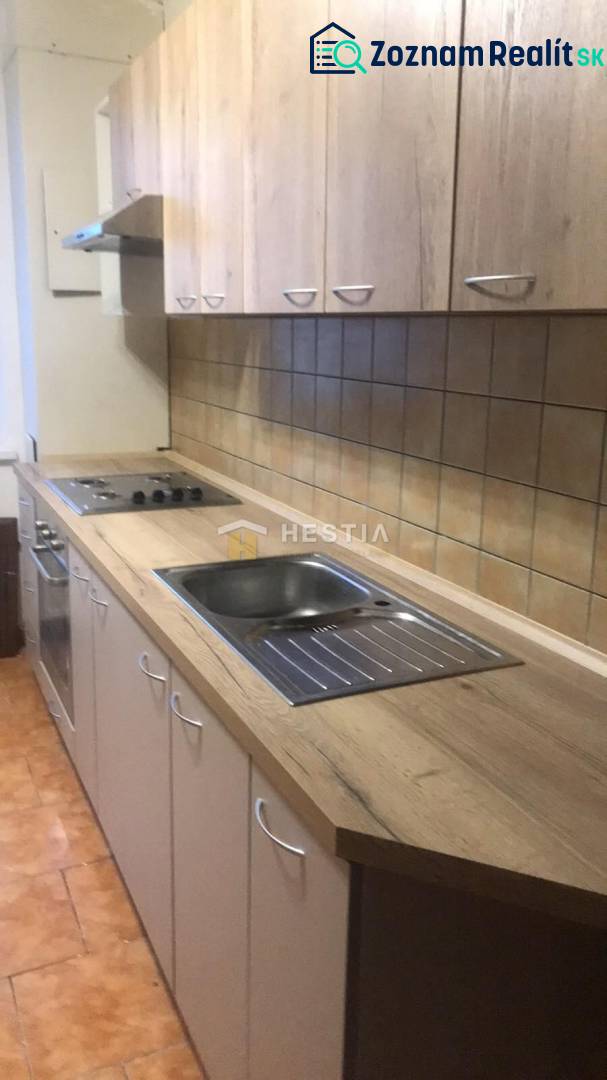 Küche in einer 2-Zimmer-Wohnung mit Holzdekorboden und hellen Möbeln.
