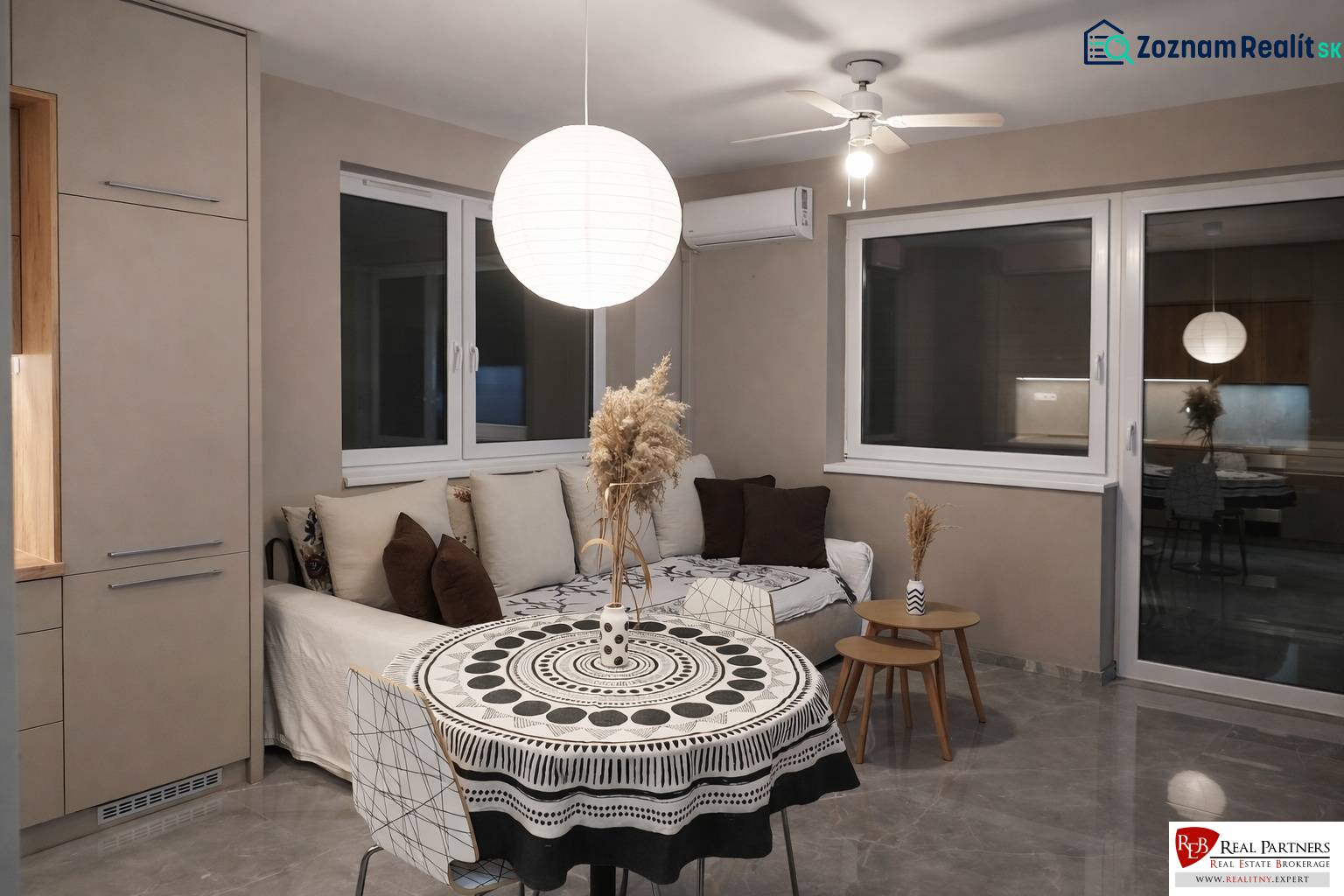 Wohnzimmer mit Sofa, rundem Tisch und dekorativer Leuchte in einer 2-Zimmer-Wohnung.