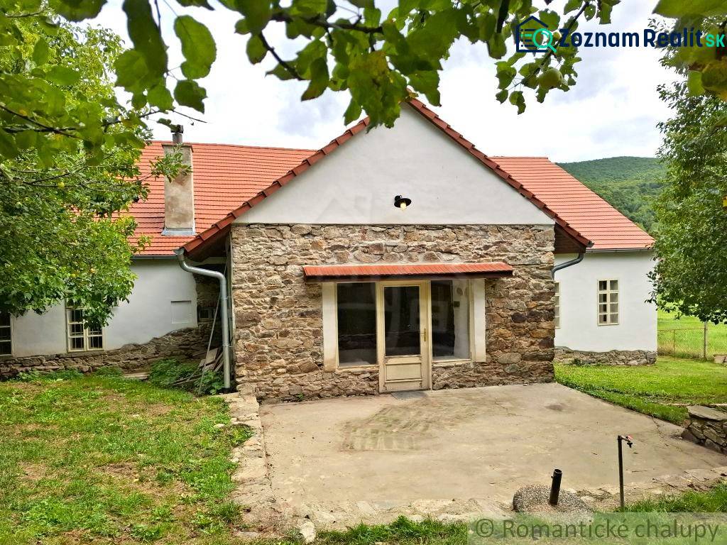Ein Einfamilienhaus in Dobroč mit einer Steinfasade, einem traditionellen Dach und einem gemütlichen Garten.