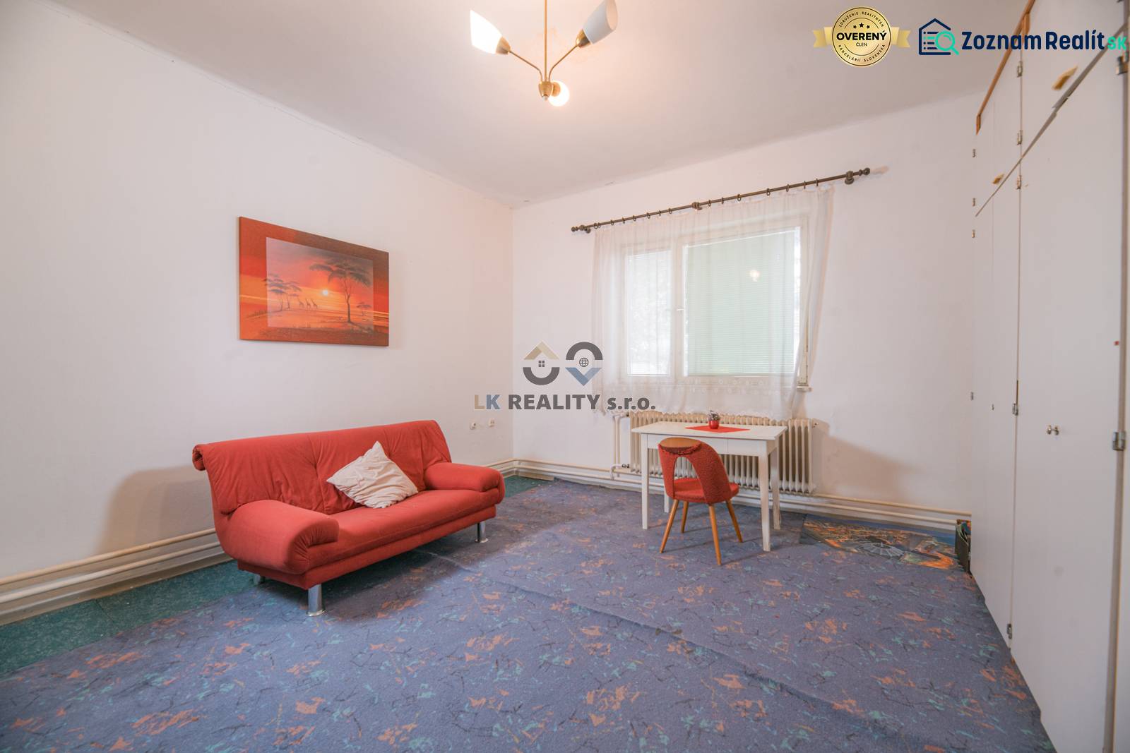 Wohnzimmer in einem Einfamilienhaus mit rotem Sofa und Tisch mit Stuhl.