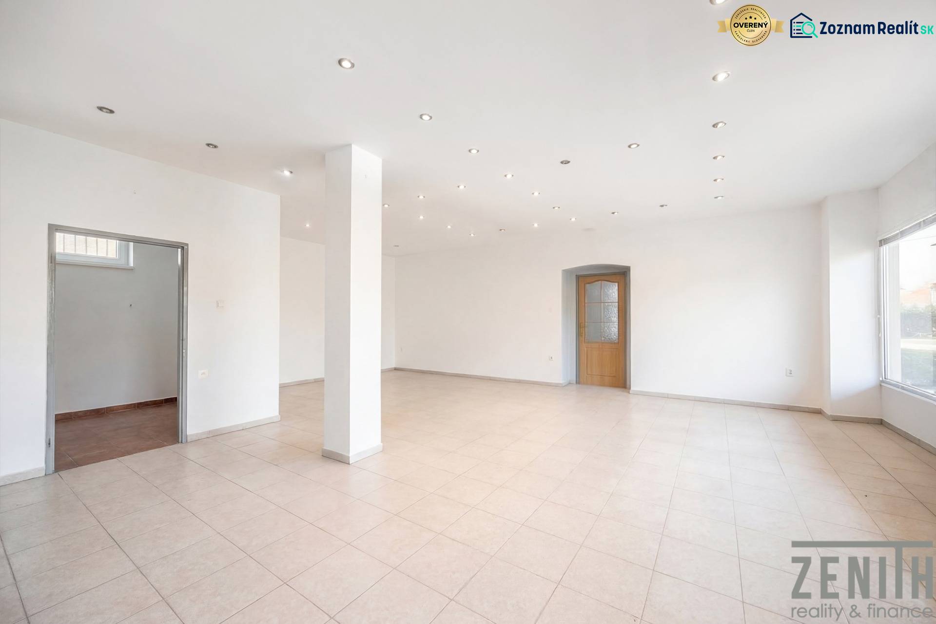 Geräumige Geschäftsräume mit weißen Wänden, Fliesenboden und eingeschalteten Deckenleuchten.