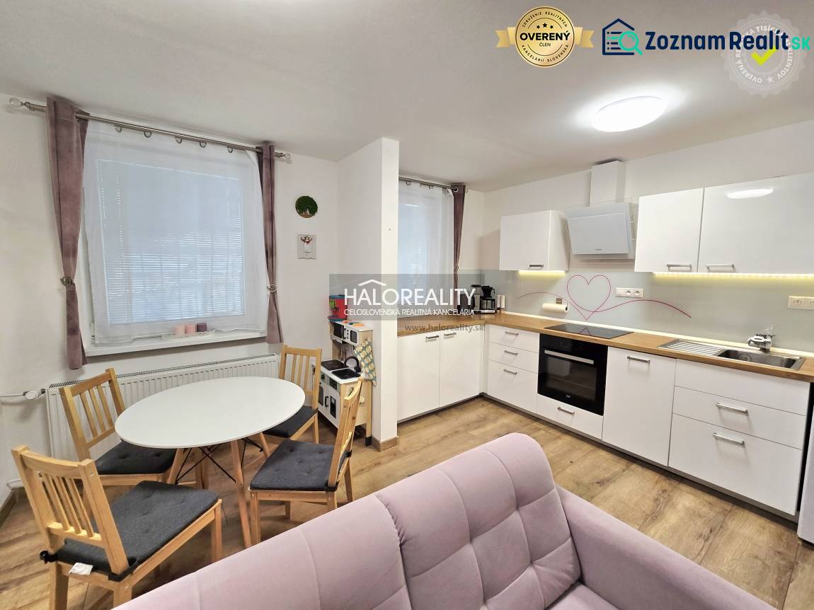 Küche in einer 3-Zimmer-Wohnung mit weißen Schränken, Boden in Holzoptik und kleinem Tisch.