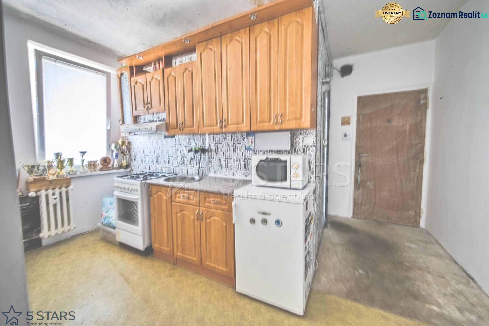 Küche mit Holzschränken und Geräten in einer Einzimmerwohnung.