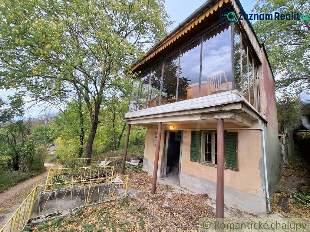 Ein Ferienhaus in Kamenín, umgeben von Grün, mit einer verglasten Terrasse und einer Zufahrtsstraße.