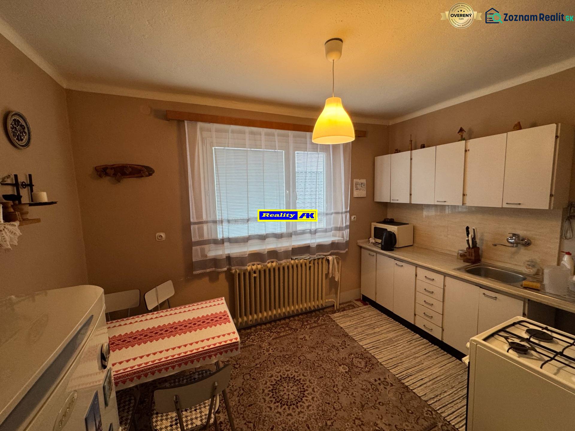 Küche in einem Einfamilienhaus mit weißen Schränken, gemustertem Teppich und Esstisch.