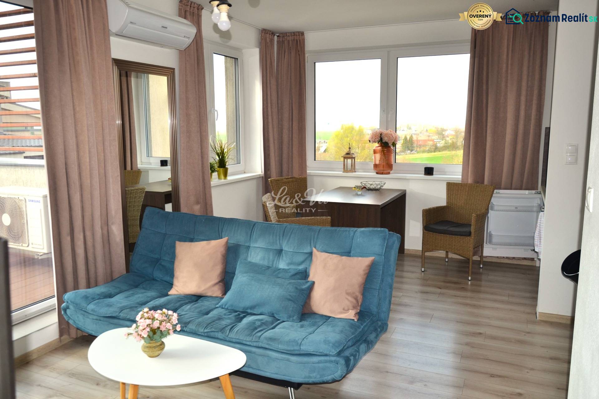 Wohnzimmer mit Sofa, Tisch, Pflanzen und Holzboden in einer Zweizimmerwohnung.