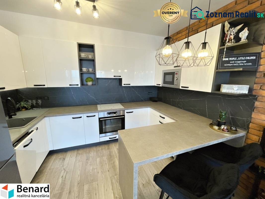 Küche in einer 2-Zimmer-Wohnung mit weißen Schränken und einem Boden in Holzoptik.