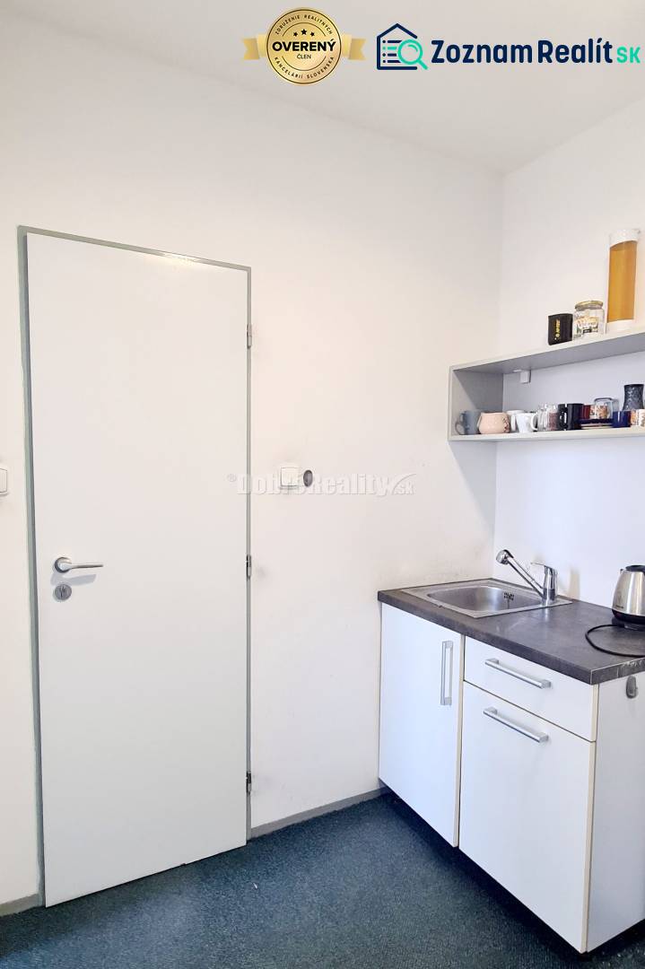 Kleine Büroküche mit Spüle, Regal und Wasserkocher.