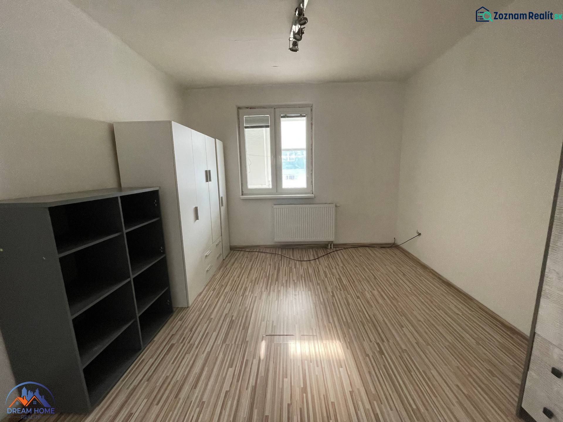 Ein Zimmer in einer 3-Zimmer-Wohnung mit einem Boden in Holzoptik und einfacher Einrichtung.