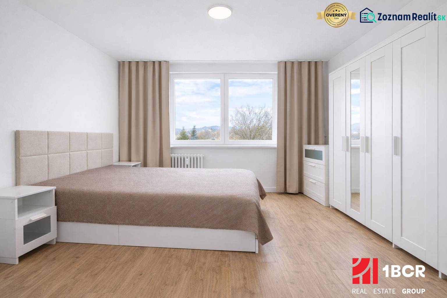 Schlafzimmer mit Doppelbett, Schrank und Holzboden in einer Zweizimmerwohnung.