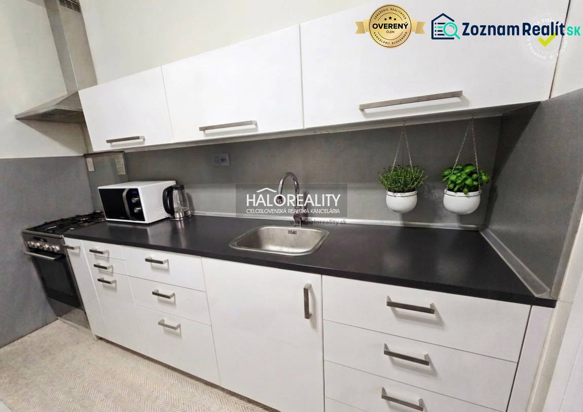 Küche mit Geräten und Kräutern in einer 4-Zimmer-Wohnung, weiße Einheit, graue Arbeitsplatte.
