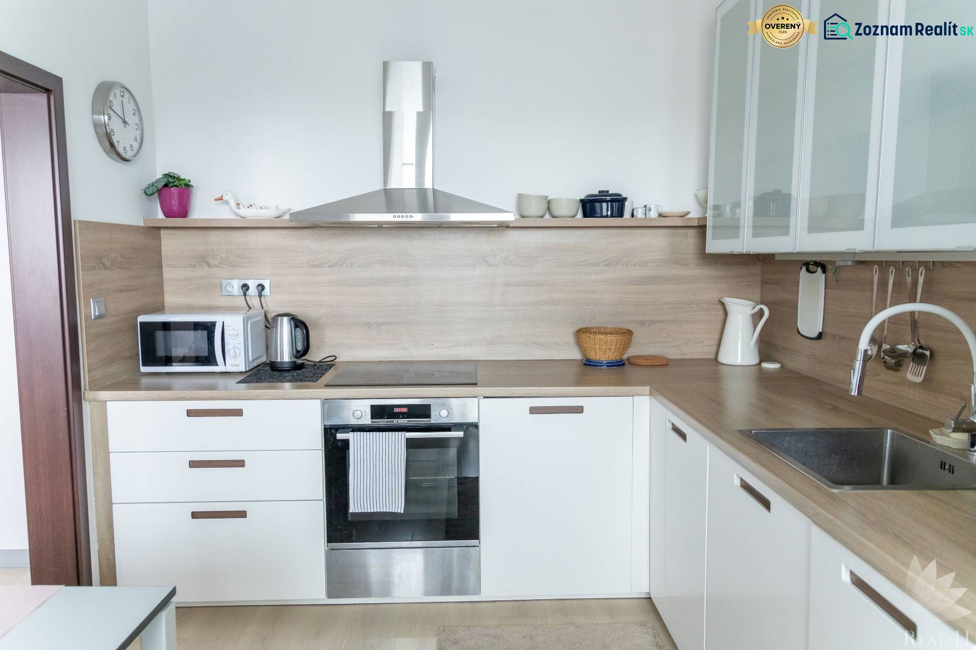Küche mit eingebauten Geräten in einer 4-Zimmer-Wohnung, Boden mit Holzdekor, helle Küchenzeile.