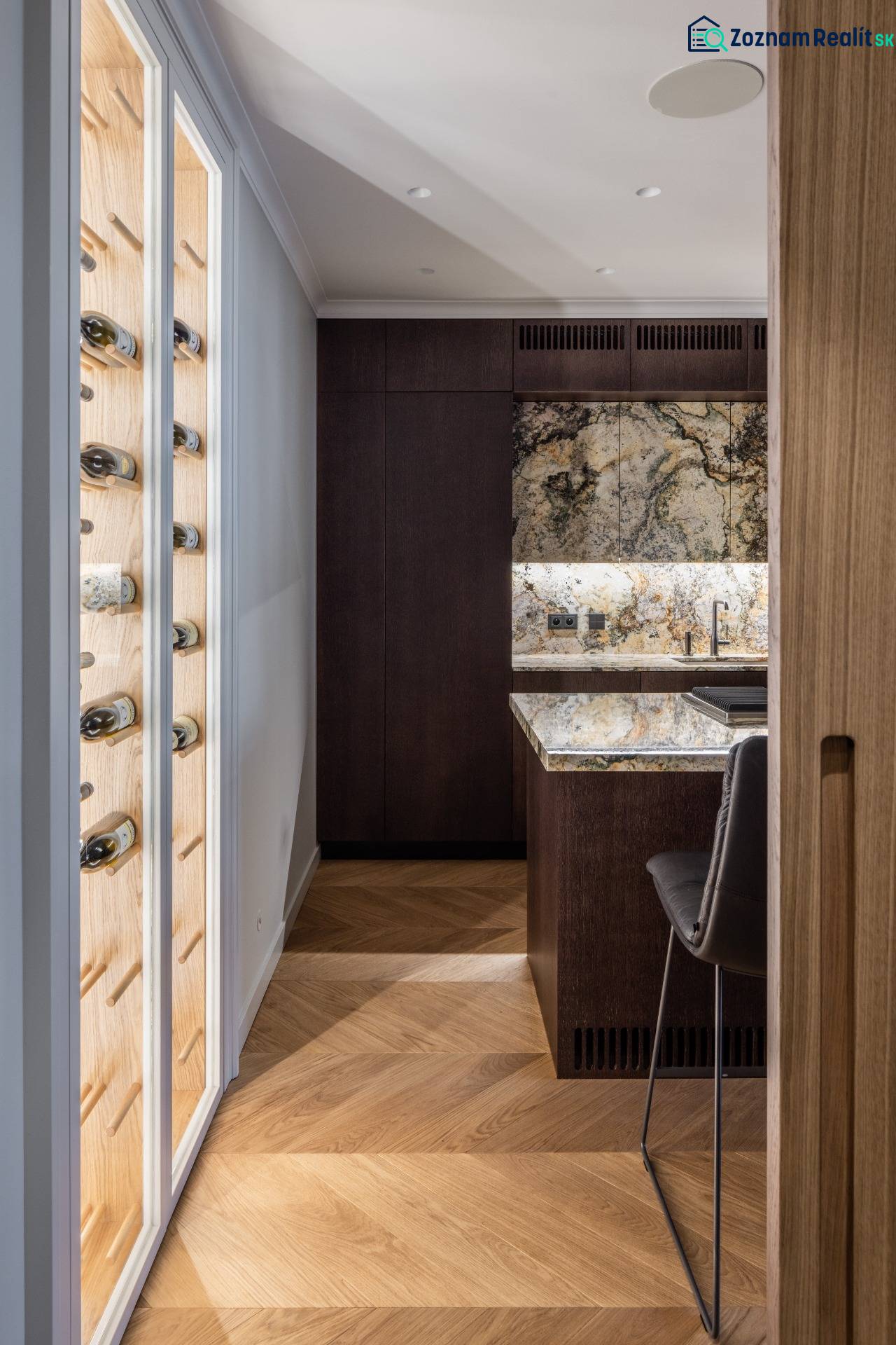 Küchenecke mit Holzboden und einer Glaswand für Wein in einer 4-Zimmer-Wohnung.