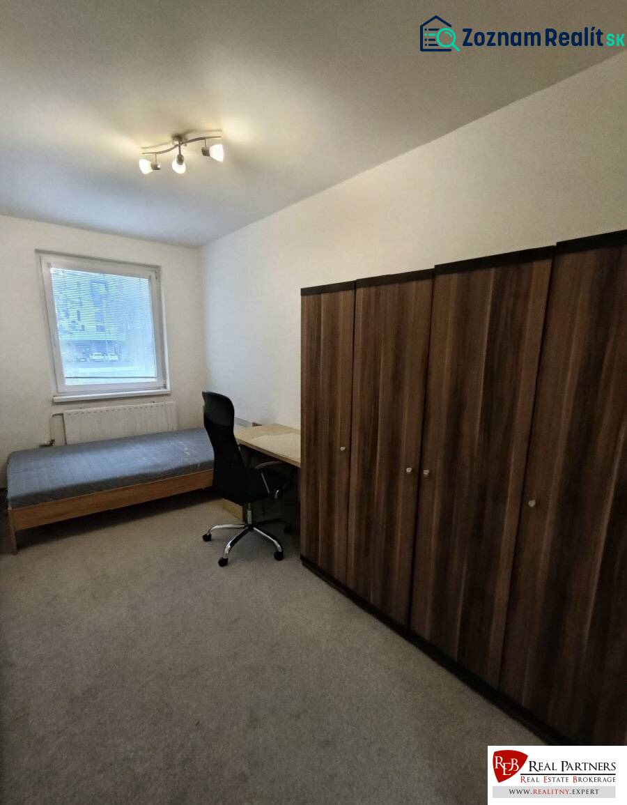 Ein Zimmer in einer 4-Zimmer-Wohnung mit einem Bett, einem Tisch, einem Stuhl und einem Schrank auf dem Teppich.